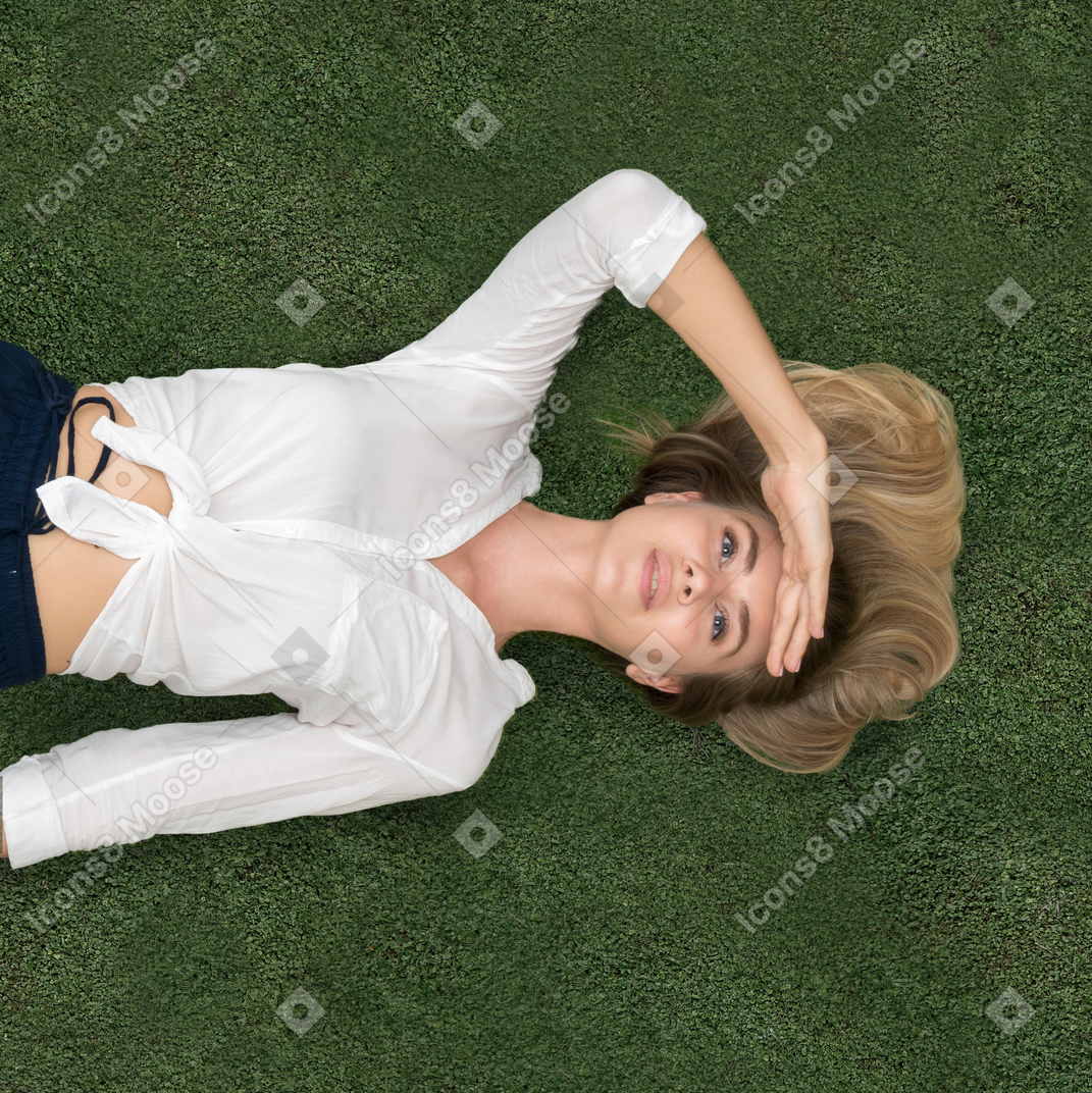 Attractive young woman lying on her back on the grass