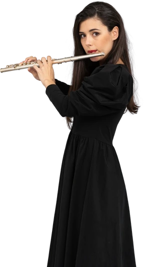 Side view of a serious young lady in black dress playing the flute