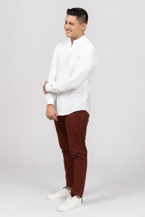 Three-quarter view of a young latino man holding his hand and smiling painfully