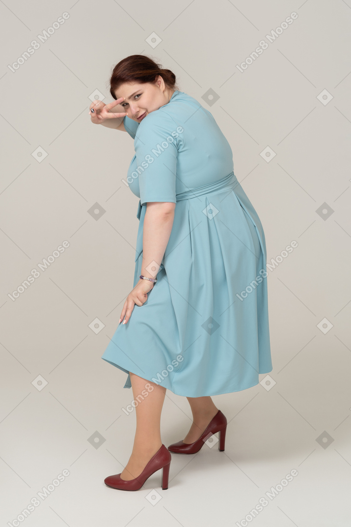 V 표시를 보여주는 파란 드레스에 여자의 측면보기
