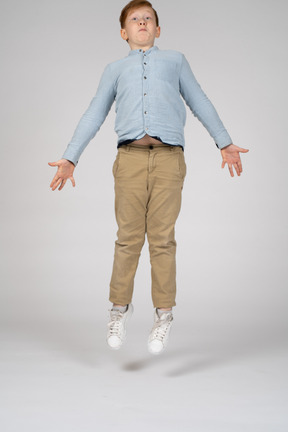 A boy in casual clothes jumping in the air