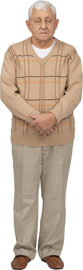Front view of an old man in casual clothes standing still with his eyes closed