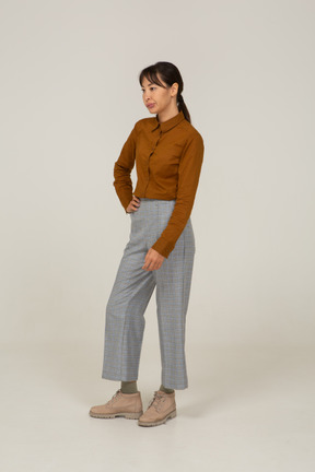 Three-quarter view of a pouting young asian female in breeches and blouse putting hand on hip