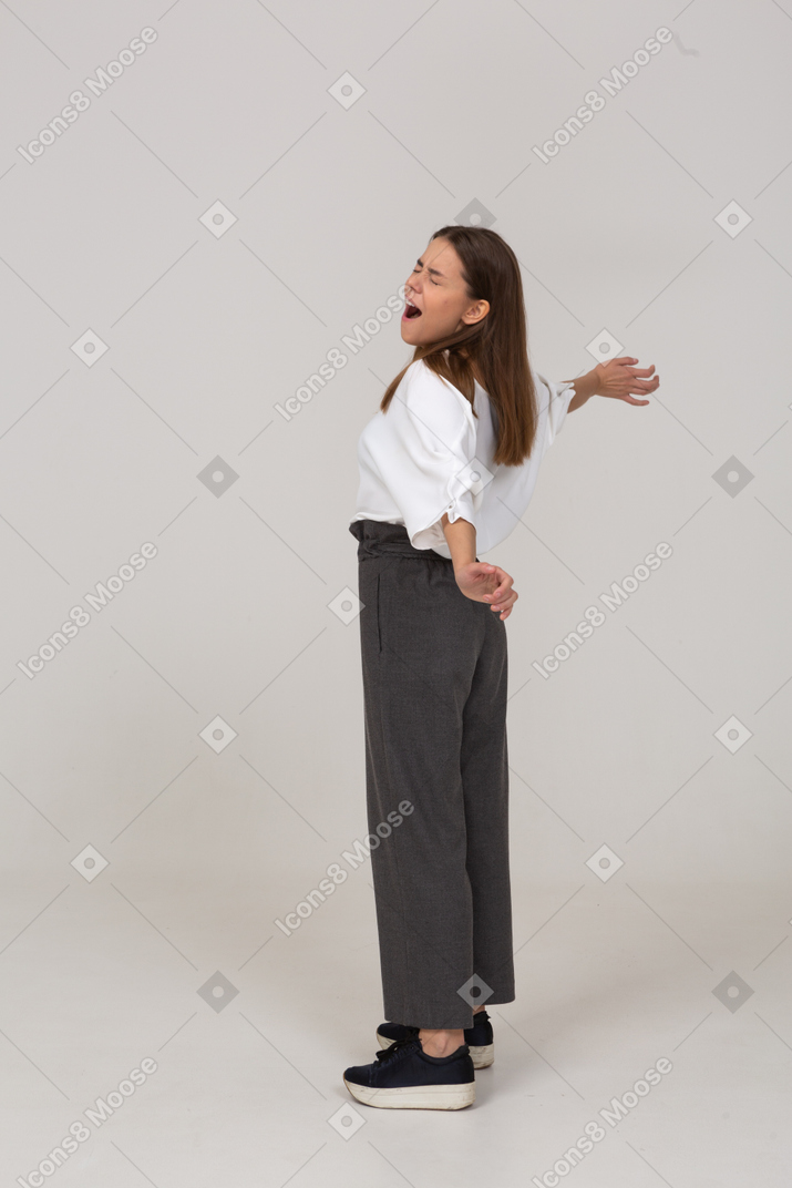 Side view of a yawning young lady in office clothing outspreading her arms