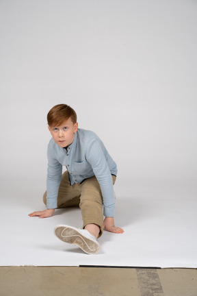 Front view of a boy in blue shirt doing a split