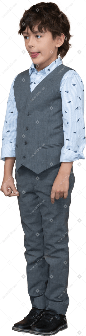 Front view of a cute boy in grey suit showing tongue