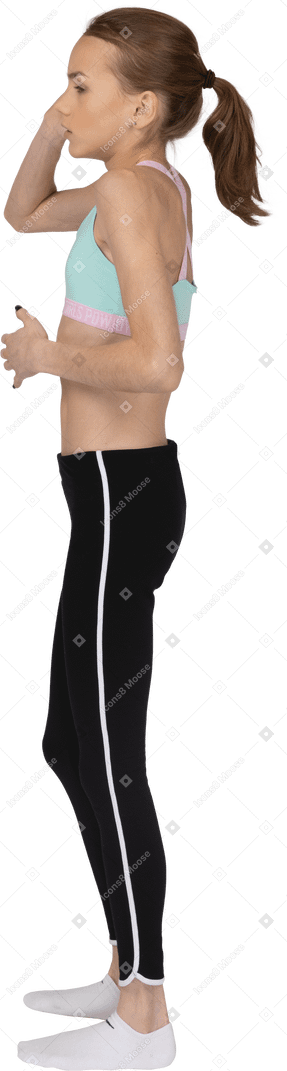 Side view of a scared teen girl in sportswear raising hand and touching stomach