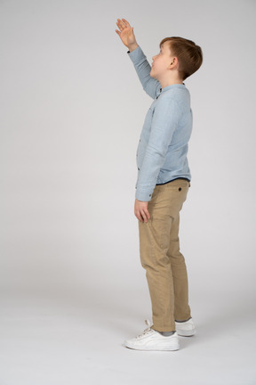 Boy in shirt and pants extending his arm upward