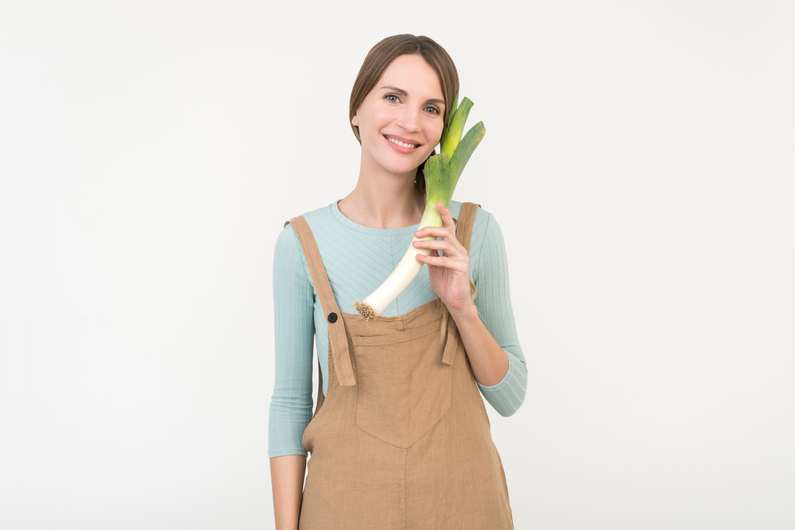 Smiling young female farmer holding leek onion