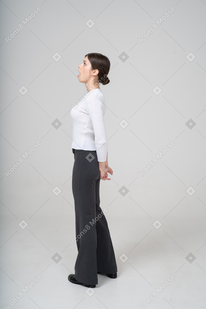 Young woman in white blouse and black pants posing in profile