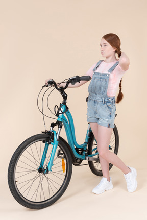 Teenage girl standing near blue bicycle