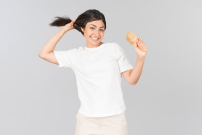 Young indian woman holding her hair and hairbrush