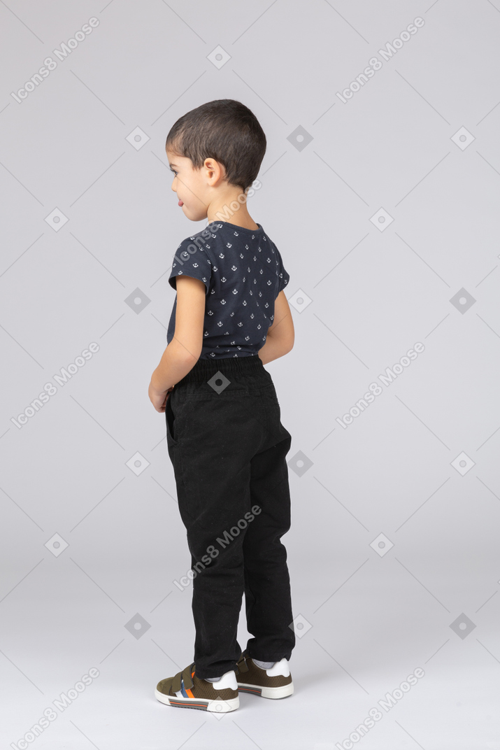 Cute boy in casual clothes standing in profile and making faces