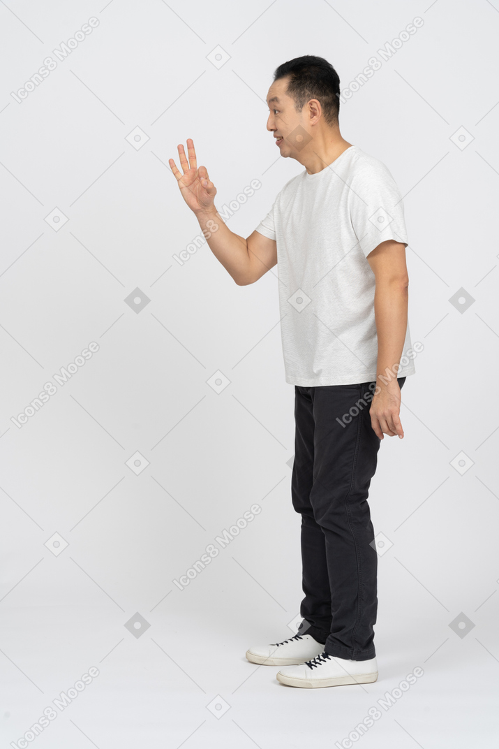 Side view of a happy man in casual clothes showing ok sign