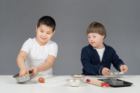 Dois garotinhos se divertindo enquanto cozinha