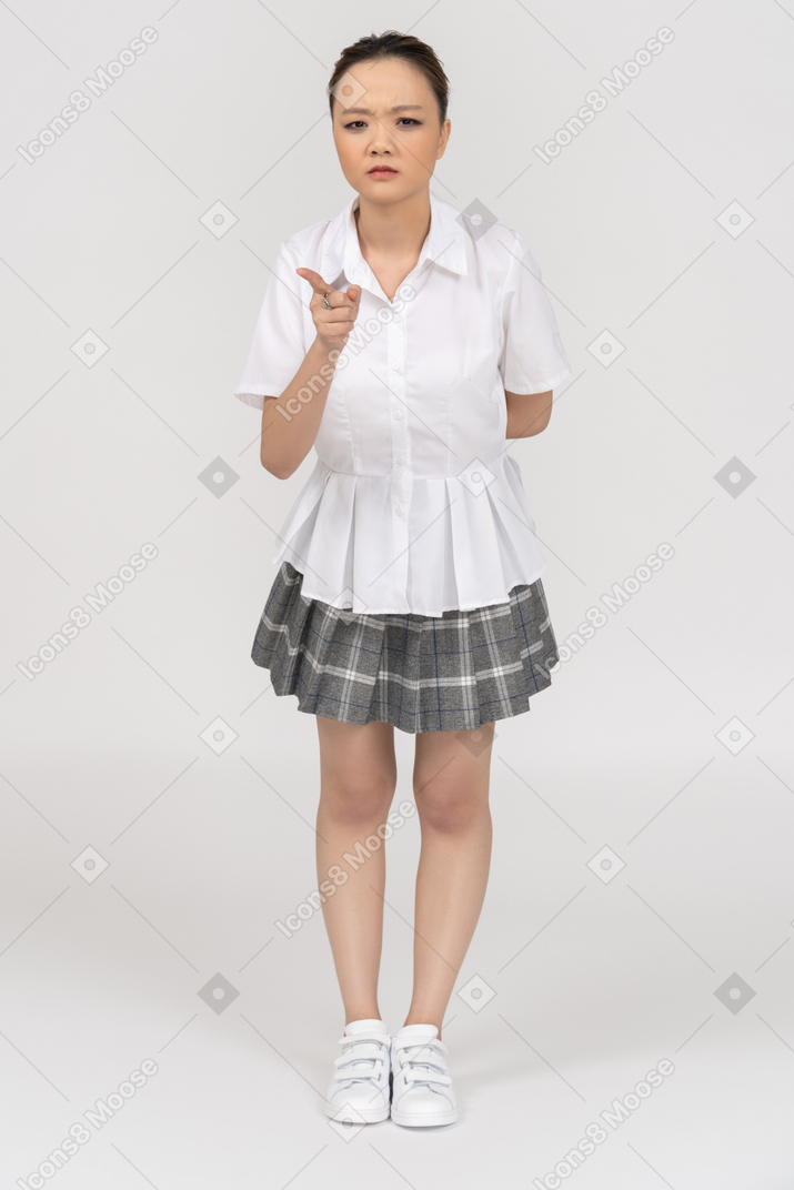 Menina asiática séria apontando com um dedo