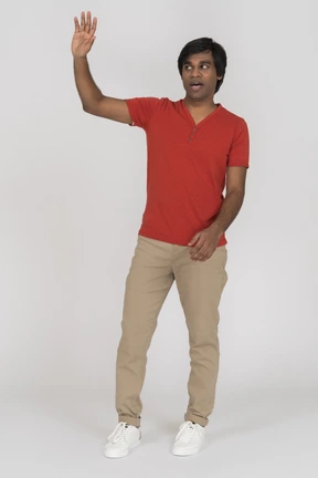 Young man waving and looking aside