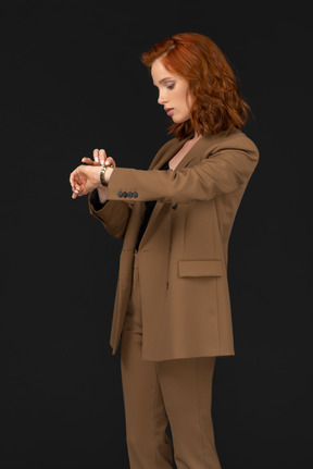 Standing half sideways woman in formal suit controlling time