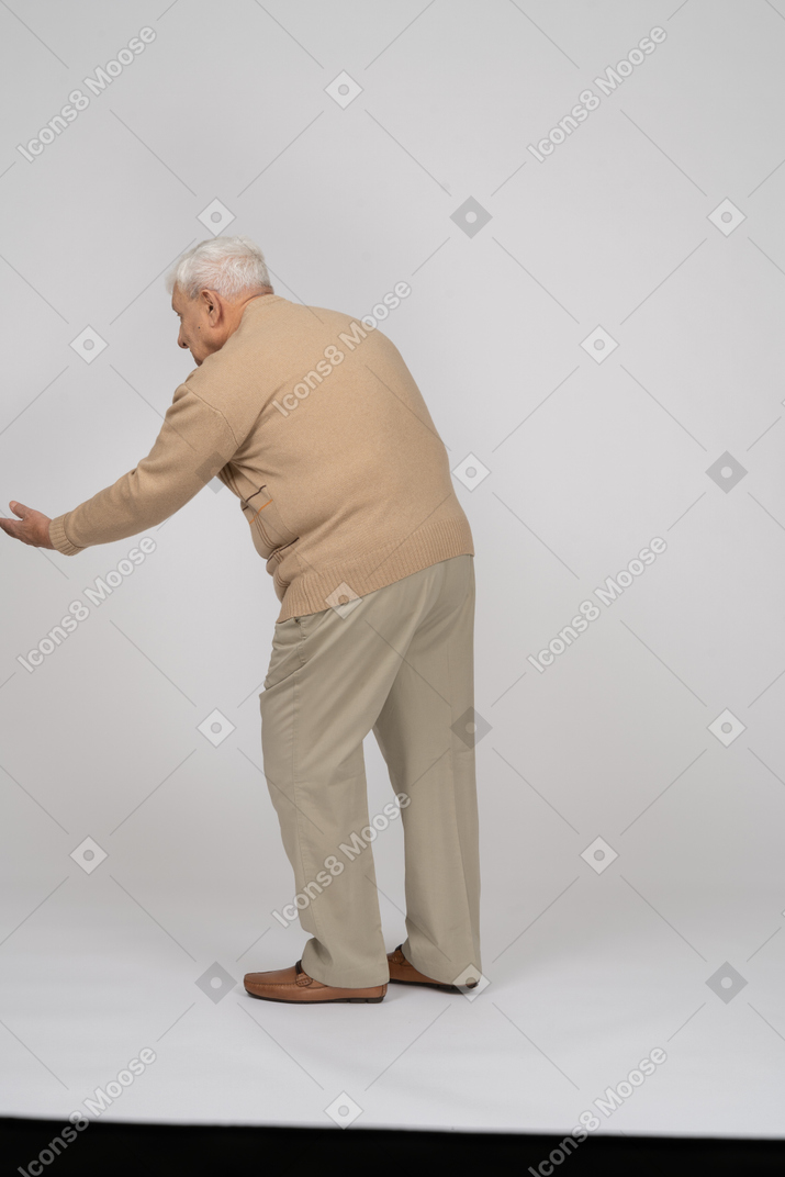 Rear view of an old man in casual clothes making welcoming gesture