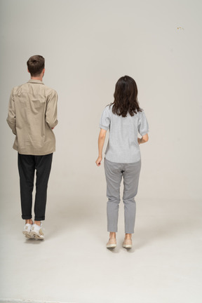 Вид сзади на молодого мужчину и женщину, стоящих на носочках