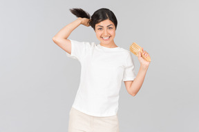 Giovane donna indiana che tiene i suoi capelli e spazzola per capelli