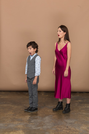 Sleepy woman in red dress and boy in grey suit vest