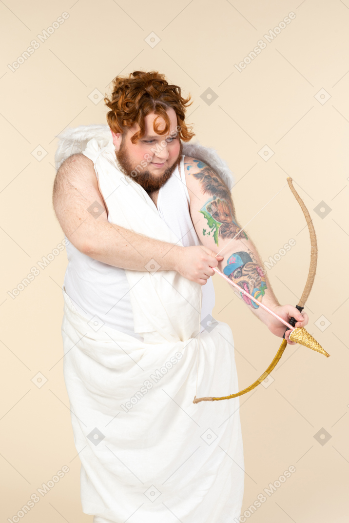 Young big man dressed as a cupid pointing with an arrow