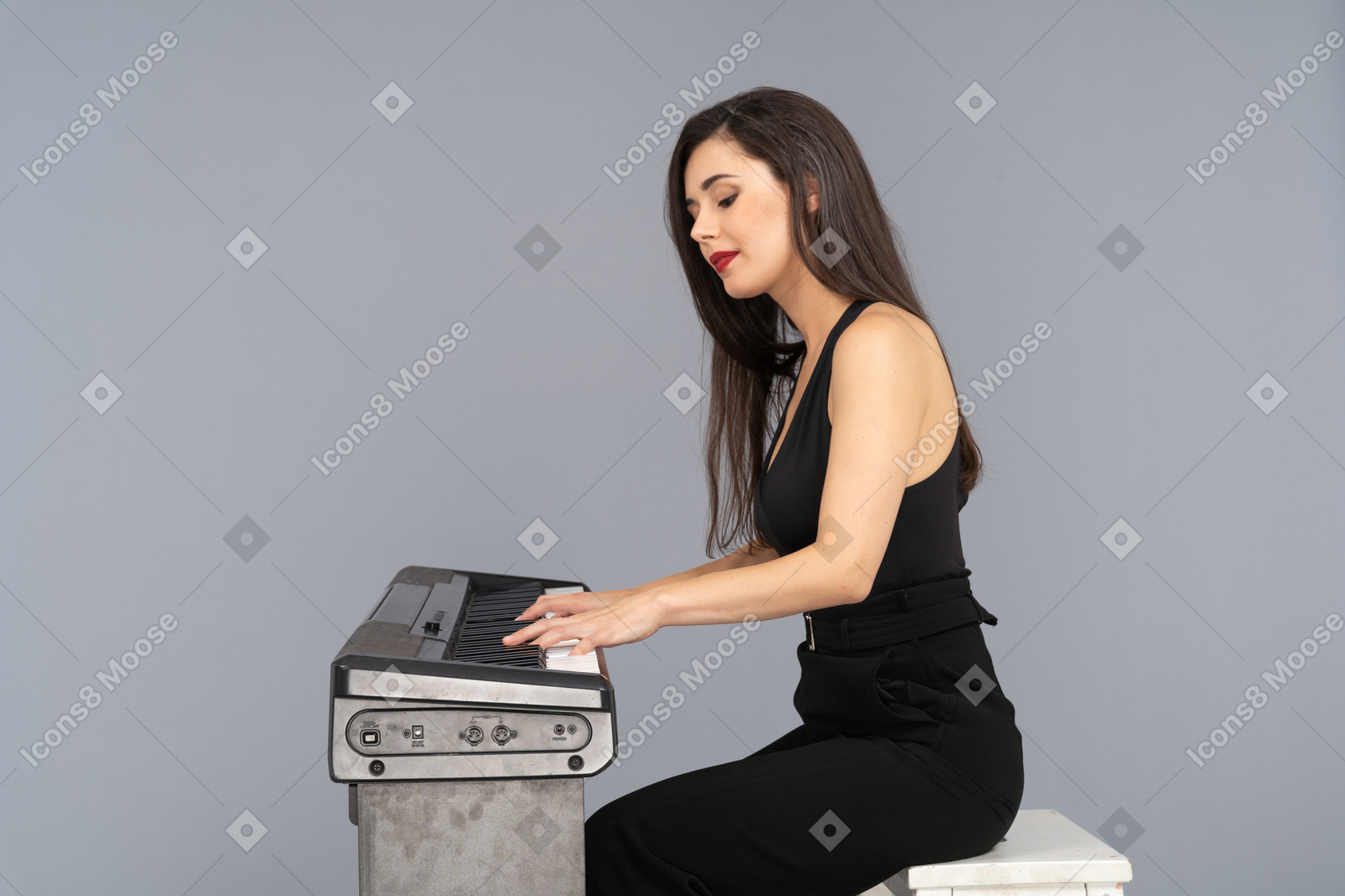 Vista lateral de uma jovem de terno preto sentada e tocando piano