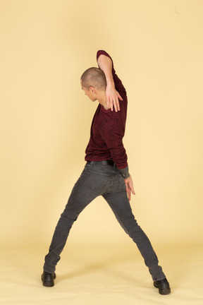 Back view of a young man in red pullover stretching his arm