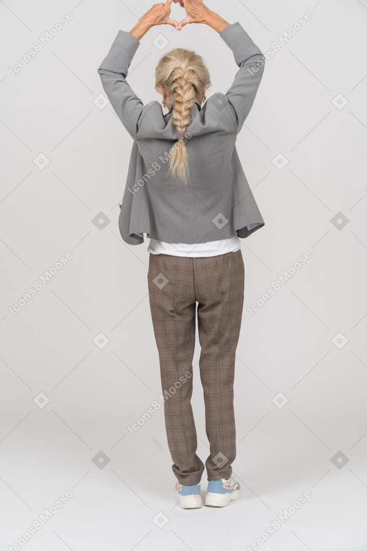 Rear view of an old lady in suit making heart sign with her fingers