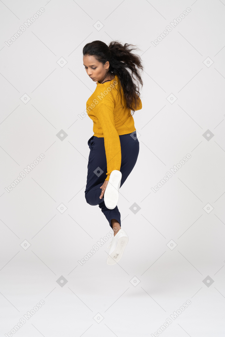 점프하고 그녀의 발을 만지려고하는 캐주얼 옷을 입은 소녀의 후면보기
