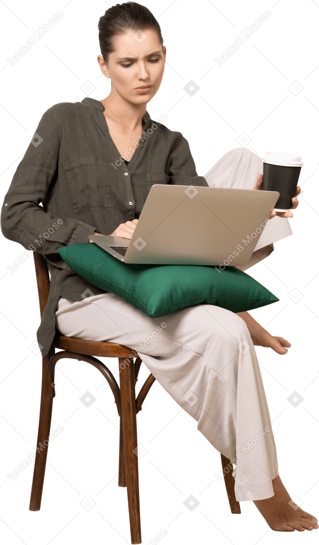 一位困惑的年轻女子坐在椅子上，拿着她的笔记本电脑和咖啡杯的前视图