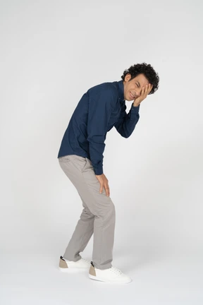 Side view of a man in casual clothes covering one eye with hand