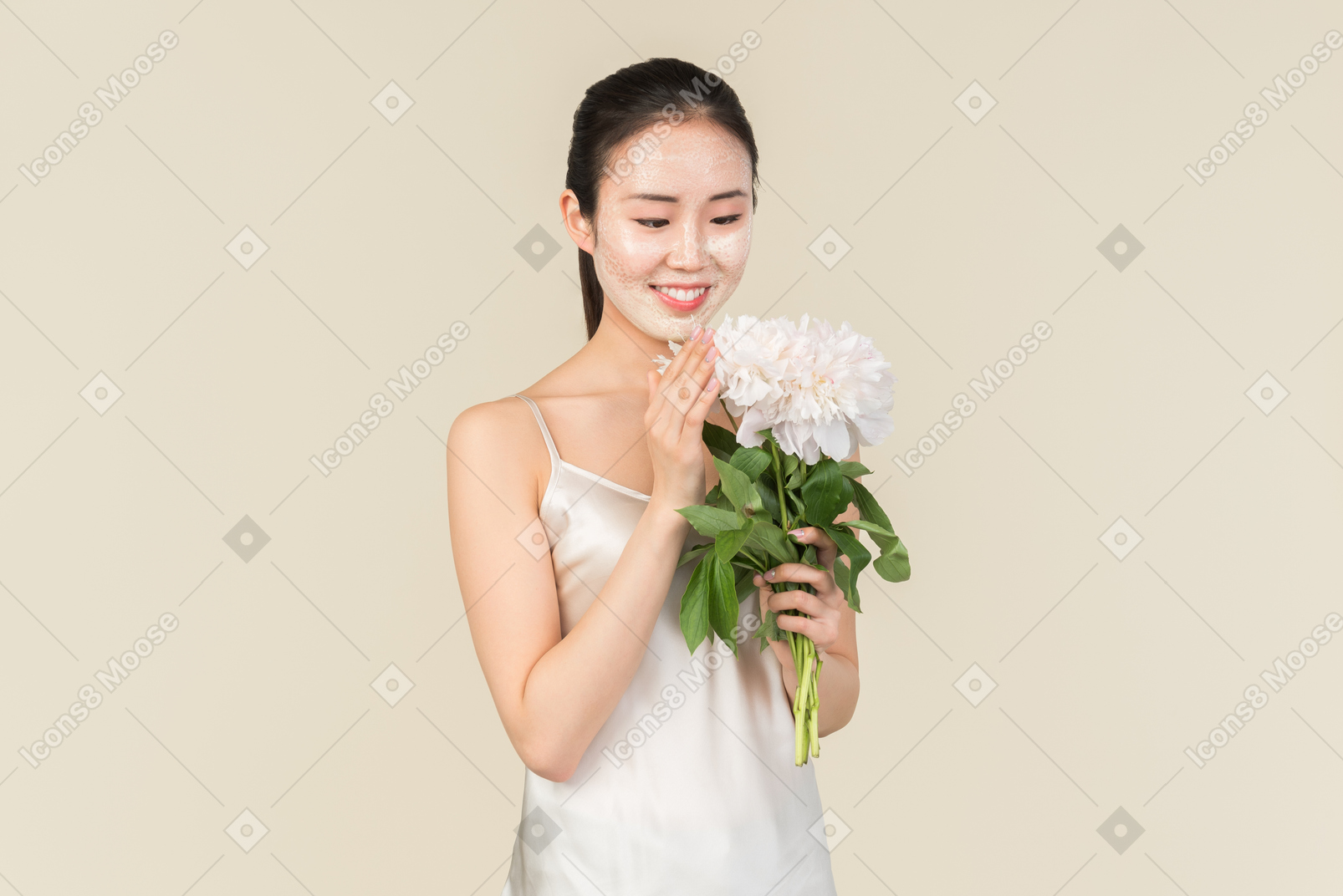Dreamy young asian woman with facial mask on holding flowers
