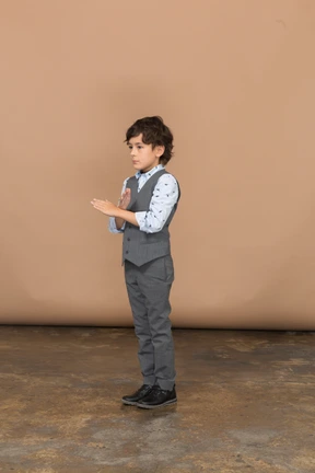 Side view of a boy in grey suit showing stop gesture