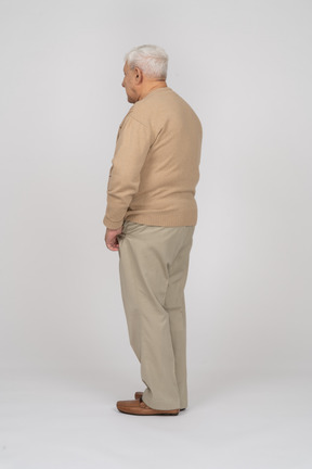 Vista laterale di un vecchio in abiti casual in piedi con le mani in tasca