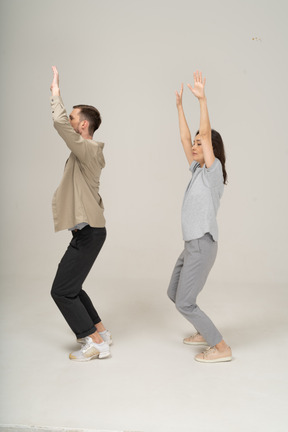 Side view of young man and woman with hands up