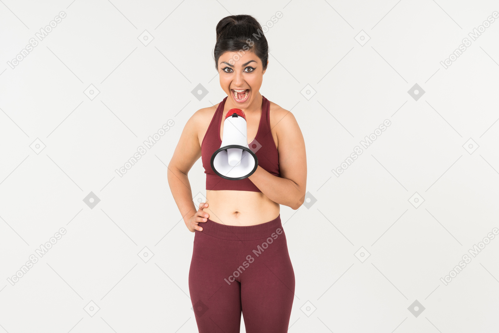 Young indian woman in sports clothes screaming using megaphone