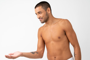 Barechested young male standing in profile with his hand elongated