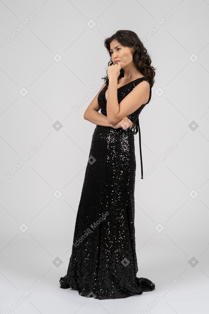 Mujer en vestido de noche negro de pie en el perfil de la cámara