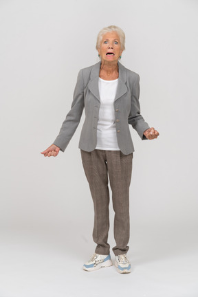 Вид спереди эмоциональной старушки в костюме, смотрящей в камеру