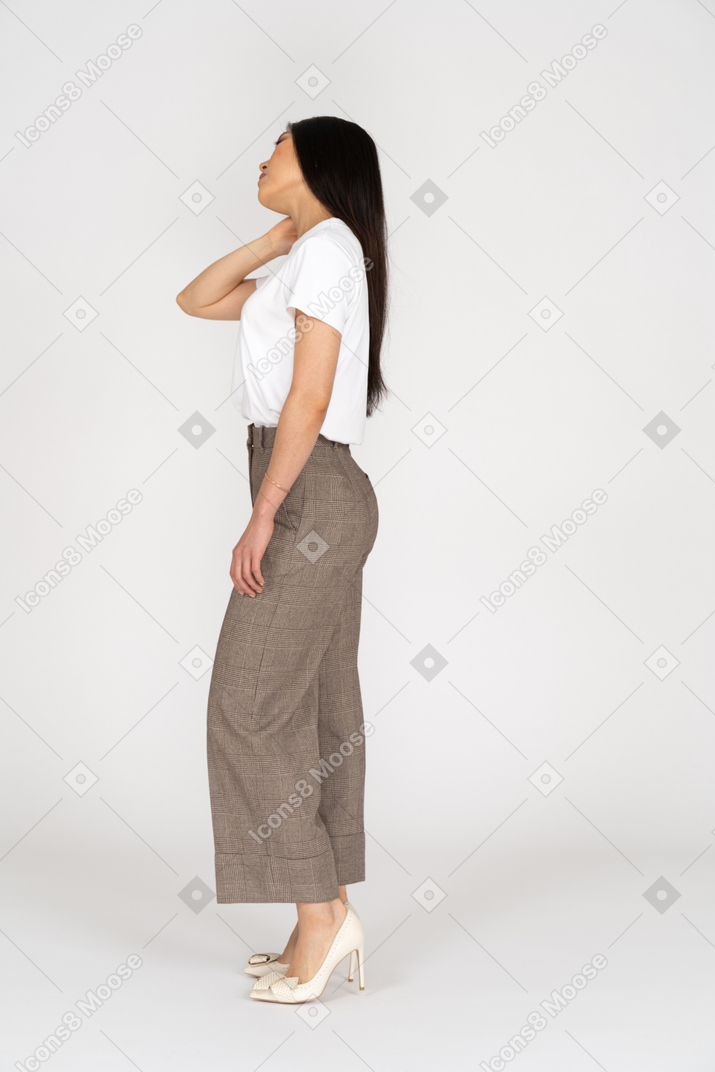 Side view of a young lady in breeches and t-shirt touching her neck