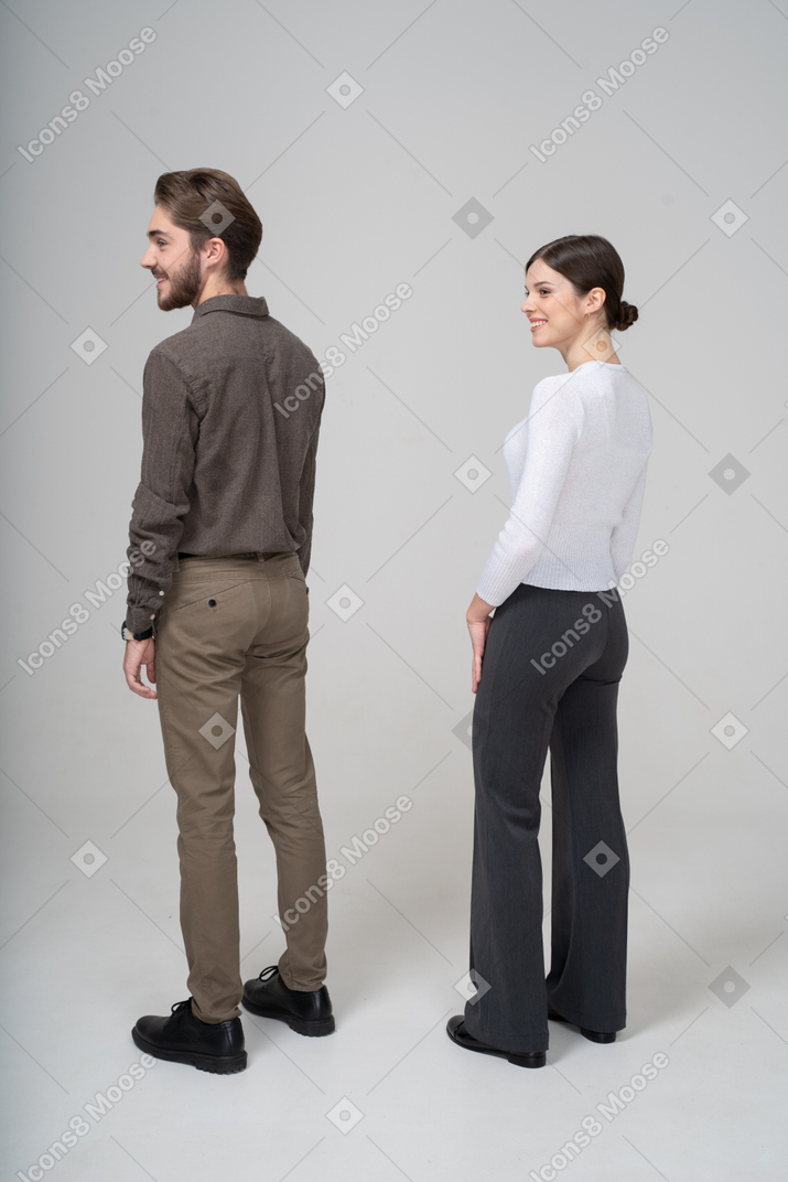 Three-quarter back view of a smiling young couple in office clothing