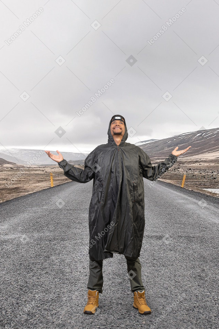 A man in a raincoat standing on a road