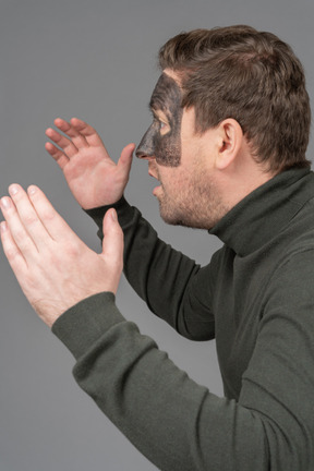 Side view of an astonished male football fan raising hands