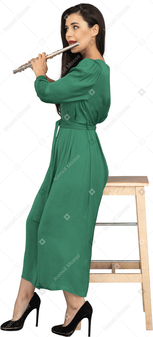 Seitenansicht einer jungen dame im grünen kleid, die auf einem stuhl sitzt, während die klarinette spielt