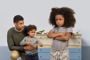 A man and two children standing in front of a dresser