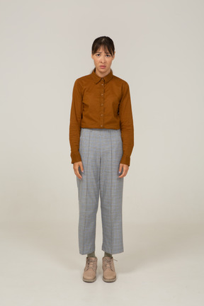 Front view of a worried young asian female in breeches and blouse standing still