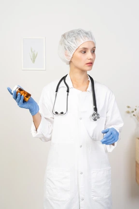 Vista frontal de una joven doctora sosteniendo un frasco de pastillas