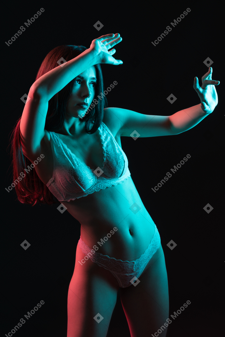 A sensual picture of a gesticulating female in underwear under neon lights